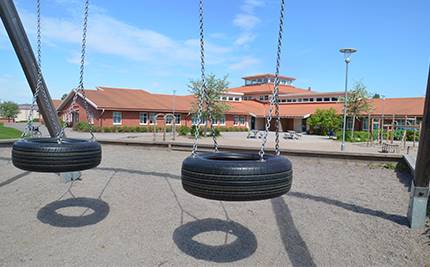 Tomma gungor framför Gunnarsbyskolan, blå himmel