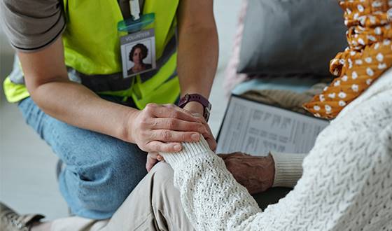 Volontär i gul väst håller äldre kvinnas hand på trygghetspunkt