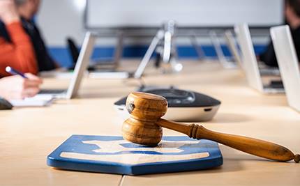 Klubba och kommunvapen i förgrunden. Mötesdeltagare i bakgrunden.