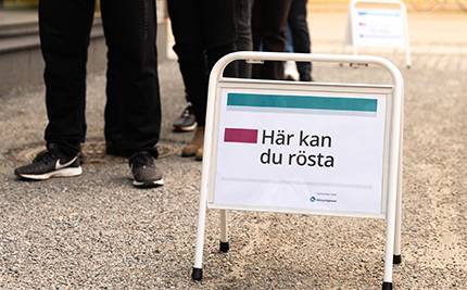 Kö vid skylt med text: Här kan du rösta"
