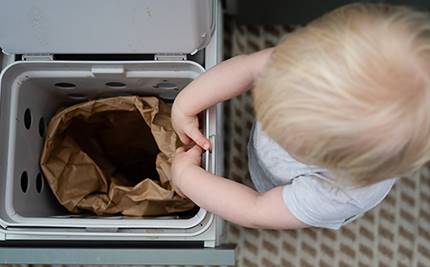 Liter barn står vid matavfallsbehållare i kök