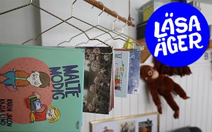 Bilderböcker hänger från klädhängare, en gosedjursapa och blå logoytp med text: Läsa äger