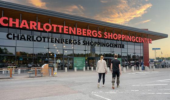 Man och kvinna går mot ingången av Charlottenbergs Shoppingcenter, kvällshimmel