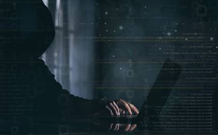 Man i mörka kläder och luva vid dator, hackerkoder i förgrunden