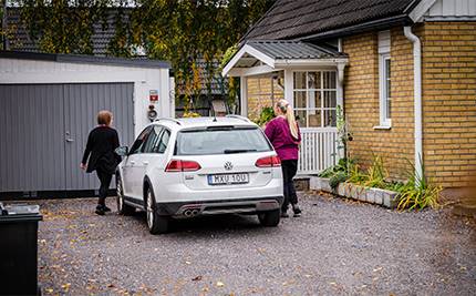 Hemtjänstpersonal går från vit bil mot tegelvilla