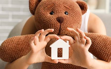 Barn håller i nalle och en form av ett hus